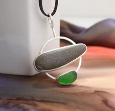 a white vase sitting on top of a wooden table next to a green glass pendant