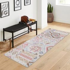 a room with a bench, rug and pictures on the wall