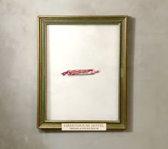 a gold frame hanging on the wall with a candy bar in it