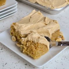 a piece of cake with peanut butter frosting on a white plate next to some plates