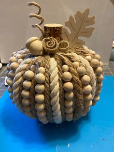 a decorative pumpkin made out of rope and wood beads with a leaf on the top