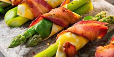 asparagus wrapped in bacon and other toppings on a stone platter, ready to be served