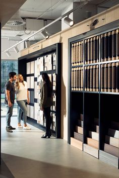 two people standing in front of a bookcase with books on the shelves and one person looking at it