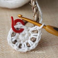 a crochet basket with yarn and scissors on it, next to a ball of thread