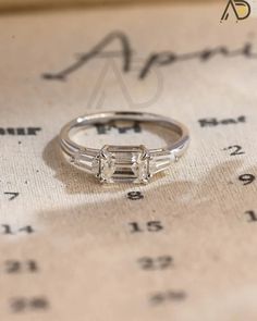 a diamond ring sitting on top of a table next to a price sheet with numbers