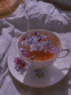 a cup filled with liquid and flowers on top of a saucer