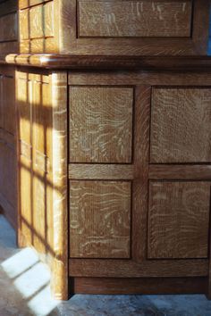 a wooden dresser sitting on top of a tile floor next to a window with the sun shining through it