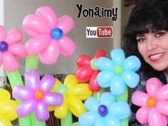 a woman is holding up some balloons with flowers on them and the words you tube above her