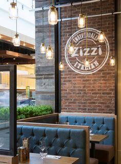 the inside of a restaurant with blue booths and lights hanging from the brick wall above