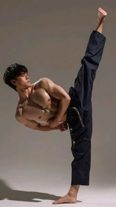 a shirtless man is doing a kickbox pose with one leg in the air