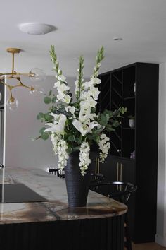 a vase filled with white flowers sitting on top of a counter