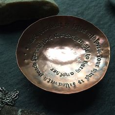 a metal plate with writing on it sitting next to some rocks and a chain necklace