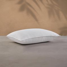 a white pillow sitting on top of a cement floor next to a tan colored wall