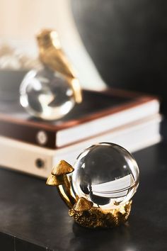 a glass ball sitting on top of a black table next to a gold figurine