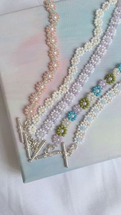 three necklaces are displayed on top of a white sheet with blue and green beads