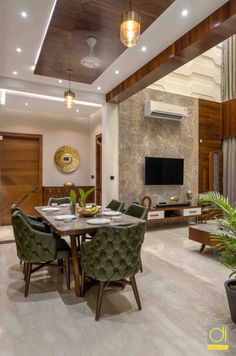 an elegant dining room with green chairs and a large tv mounted on the wall above it