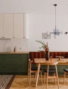 a kitchen with green cabinets and wooden table surrounded by black chairs, an area rug on the floor