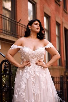 a woman in a wedding dress posing for the camera with her hands on her hips