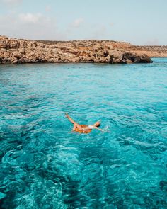 a woman floating in the ocean with her arms outstretched