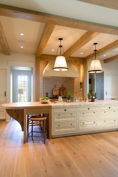 a large kitchen with an island in the middle and two pendant lights hanging from the ceiling