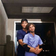 two men in scrubs standing next to each other with their arms around one another