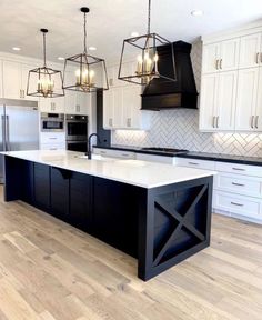 a large kitchen with an island in the middle and two pendant lights hanging from the ceiling