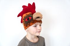 a young boy wearing a red and brown rooster hat