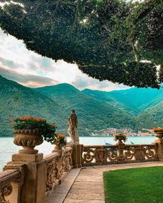 a statue on a balcony overlooking the water and mountains