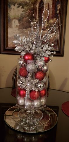 a glass vase filled with ornaments on top of a table