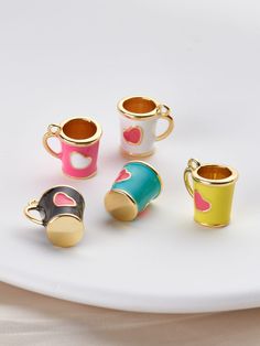 four different colored cups sitting on top of a white plate with gold trimmings