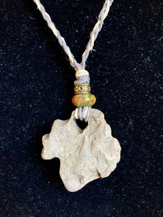 a necklace with a rock on it and two beads hanging from the front, along with a rope