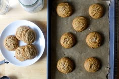 some cookies are sitting on a baking sheet next to a bowl of milk and spoons