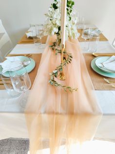 the table is set with white flowers and greenery, along with an umbrella shaped centerpiece