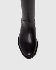 Raina is our take on the classic riding boot. Crafted from a super durable yet luxuriously soft black leather, this timeless straight shaft tall boot is designed with a curved topline that dips at the front and back for a flattering look, western-inspired pattern and stitch detailing, an extended leather welt with tonal stitch details, and a black leather stacked 20mm heel for a slight amount of lift. The classic menswear-inspired details on the outsole include stitching and half toplift for an Sleek Tall Leather Boots, Tall Black Leather Heeled Boots, Black Leather Mid-calf Tall Boots, Classic Black Ankle-high Moto Boots, Tall Boots Equestrian Black, Black Boots Tall, Men Store, Denim Shoes, Menswear Inspired