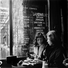 two people sitting at a table in front of a window with menus on it