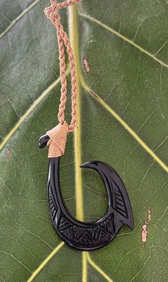 a black pendant on a green leaf