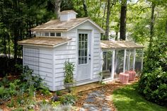 a small white shed sitting in the middle of a forest