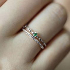 a woman's hand with a green ring on it