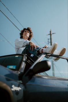 a person sitting on the hood of a car with their feet up in the air