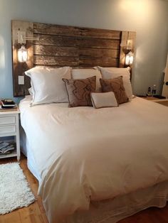 a bed with white sheets and pillows on top of it in a bedroom next to a wooden headboard