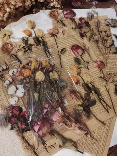 dried flowers are sitting on top of an old book with torn pages and other papers