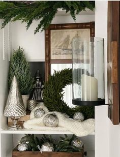 christmas decorations are displayed on shelves in the living room, with candles and evergreen branches