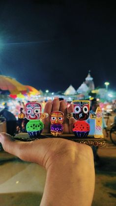 a hand is holding several small toy figures in front of an outdoor tent at night