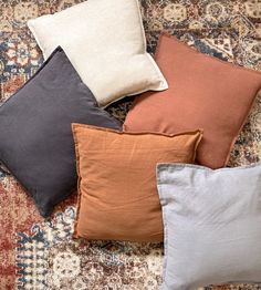 four different colored pillows sitting on top of a rug