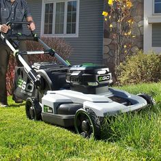 a man mowing the grass in front of his house with a lawnmower