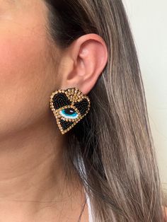 Add a modern and beautiful touch to your outfit with these beautiful evil eye protection dangle earrings or Sacred Heart earrings. Each pair of heart earrings is meticulously hand-embroidered with calibrated beads and Czech crystals, ensuring exceptional quality. The primary color is black with gold details and the eye color is blue. These handmade earrings are not only beautiful, but also offer protection, making them a stylish and meaningful choice. Add a touch of style and meaning to your han Unique Handmade Heart Earrings, Handmade Trendy Heart Drop Earrings, Trendy Handmade Heart Drop Earrings, Elegant Beaded Heart Earrings, Trendy Heart-shaped Pierced Earrings, Party Heart Drop Earrings With Ear Wire, Unique Heart-shaped Earrings, Handmade Heart-shaped Trendy Earrings, Handmade Heart Drop Earrings For Party