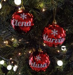 three red ornaments hanging from a christmas tree