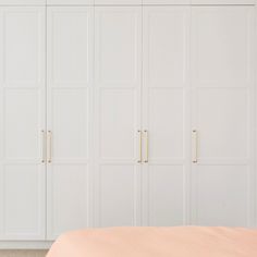 a bedroom with white cabinets and pink sheets