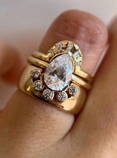 a close up of a person's hand holding a ring with a diamond on it