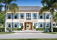 a large white house with blue shutters and palm trees